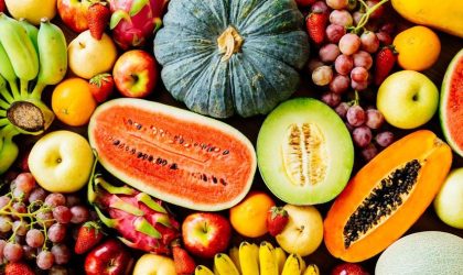 Macam-macam buah segar berwarna-warni dengan berbagai jenis seperti apel, jeruk, anggur, pisang, dan buah tropis lainnya di atas meja.