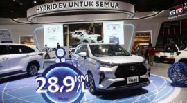 Pengunjung melihat Toyota Veloz Hybrid di showroom sambil memperhatikan informasi harga dan estimasi pajak tahunan kendaraan hybrid tersebut.