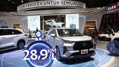 Pengunjung melihat Toyota Veloz Hybrid di showroom sambil memperhatikan informasi harga dan estimasi pajak tahunan kendaraan hybrid tersebut.