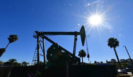 "pompa minyak di bawah sinar matahari dengan latar langit cerah menggambarkan industri minyak dunia"