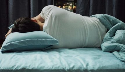 Pria tidur di tempat tidur dengan posisi terlentang di kamar yang tenang pada malam hari