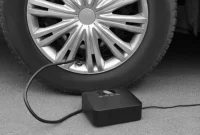Pompa angin elektrik portable mengisi ban mobil di jalan(NewAfrica/Depositphotos)