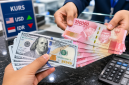 Ilustrasi Petugas menunjukkan uang rupiah saat transaksi penukaran dengan dolar AS di counter bank.