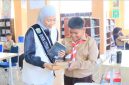 Bunda Literasi Sri Kartini Alfin mendampingi murid SD dalam kegiatan literasi di perpustakaan.