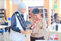 Bunda Literasi Sri Kartini Alfin mendampingi murid SD dalam kegiatan literasi di perpustakaan.