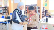 Bunda Literasi Sri Kartini Alfin mendampingi murid SD dalam kegiatan literasi di perpustakaan.