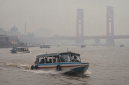 Kabut asap menyelimuti Sungai Musi, Palembang, sementara speedboat tetap melayani penumpang.