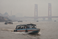 Kabut asap menyelimuti Sungai Musi, Palembang, sementara speedboat tetap melayani penumpang.
