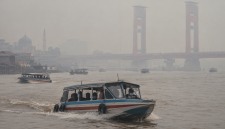 Kabut asap menyelimuti Sungai Musi, Palembang, sementara speedboat tetap melayani penumpang.