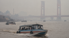 Kabut asap menyelimuti Sungai Musi, Palembang, sementara speedboat tetap melayani penumpang.