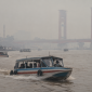 Kabut asap menyelimuti Sungai Musi, Palembang, sementara speedboat tetap melayani penumpang.