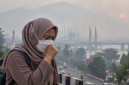 Ilustrasi warga menggunakan masker di tengah kabut asap akibat karhutla.( Foto AI Inbrita)