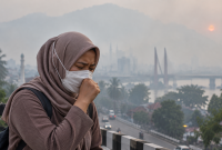 Ilustrasi warga menggunakan masker di tengah kabut asap akibat karhutla.( Foto AI Inbrita)